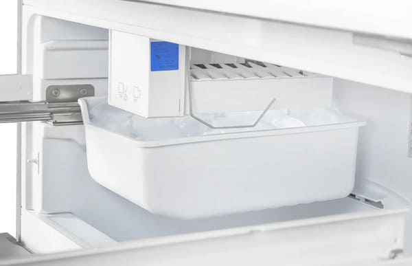 Close-up of the built-in ice maker inside the FORNO 36-inch French door refrigerator in stainless steel, showcasing the compact design and ice storage bin.