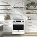 Lifestyle image of the FORNO 30-Inch Induction Range in white, shown in a modern kitchen setting with cabinetry and countertops for context.