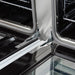 Close-up of the oven door hinges on the FORNO Antico 48-Inch Dual Fuel Range in white, highlighting the heavy-duty construction and smooth, durable hinge mechanism for reliable performance.
