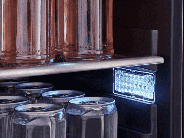 Interior view of the Zephyr ADA-compliant beverage cooler illuminated with cloud white LED lighting, highlighting beverage storage on wooden racks.